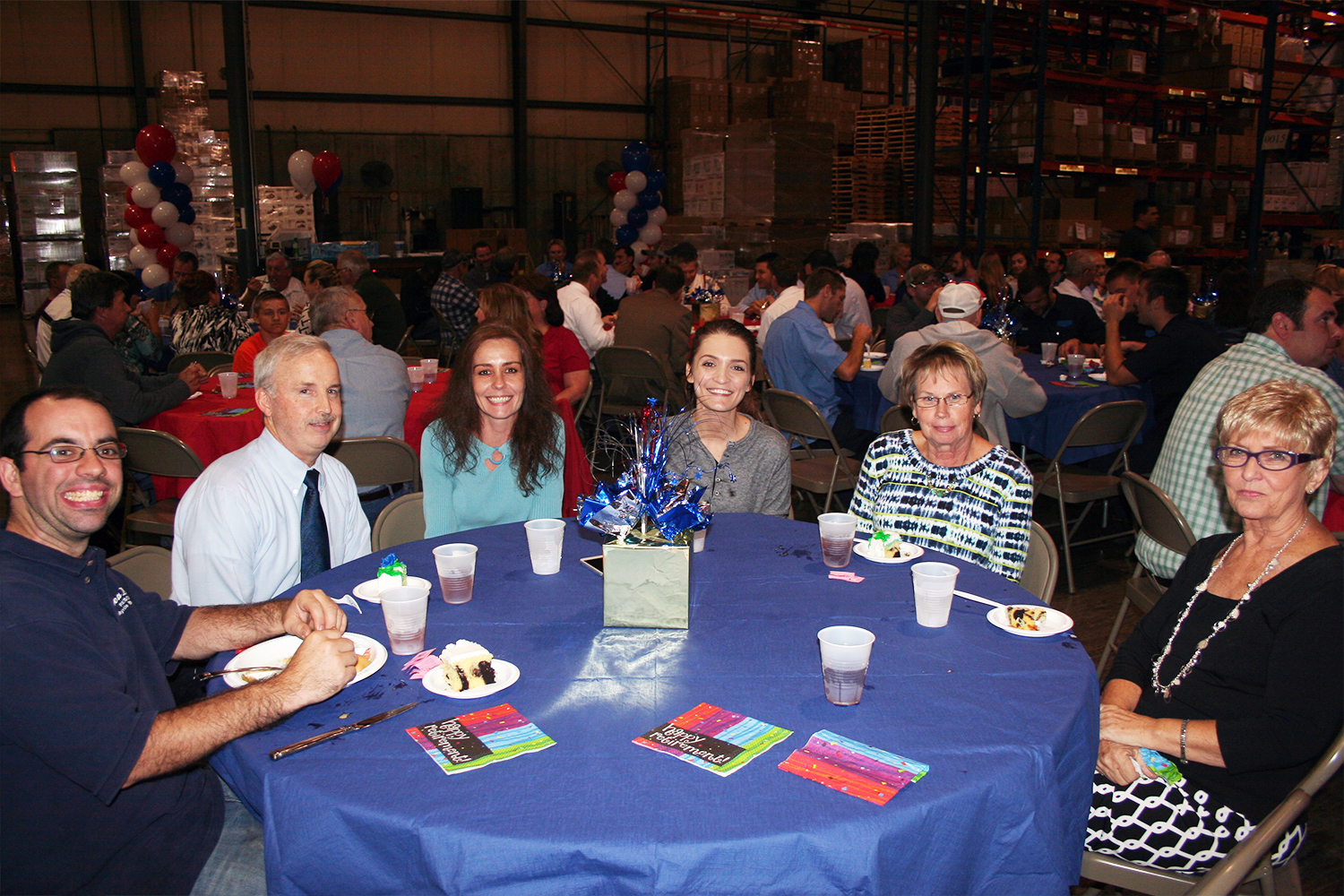 Group of Buckeye employees sitting at a table in the warehouse decorated to celebrate a retirement.