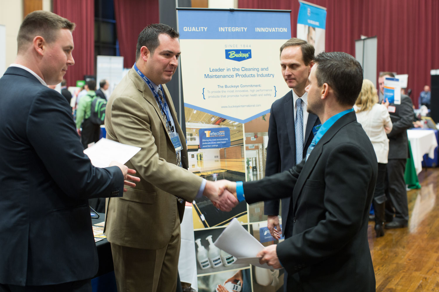 Four men talking and shaking hands at a career fair.