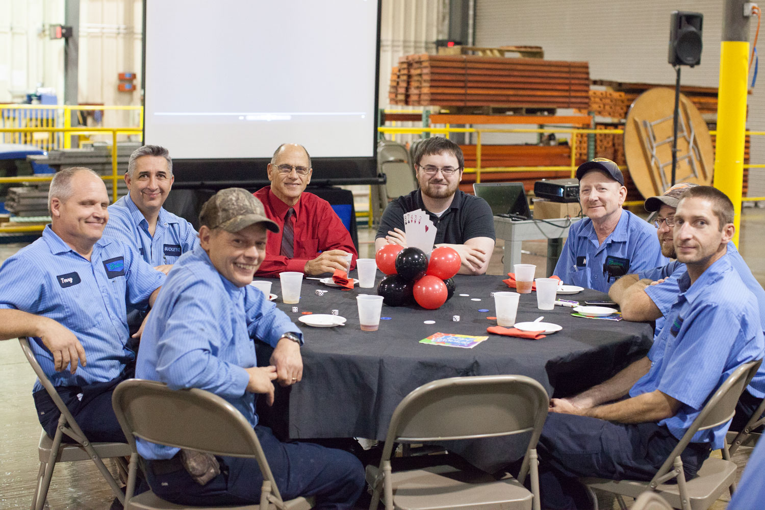 Group of warehouse employees sitting at a table celebrating a retirement