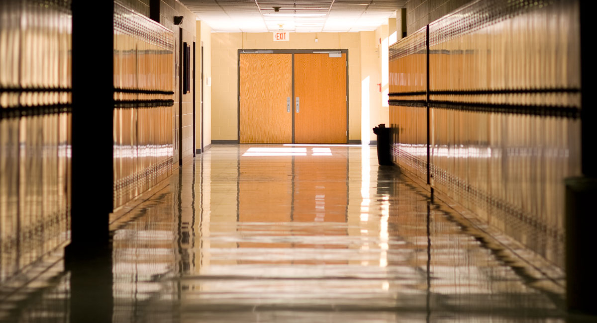 An empty school hallway lined with lockers and a shiny floor