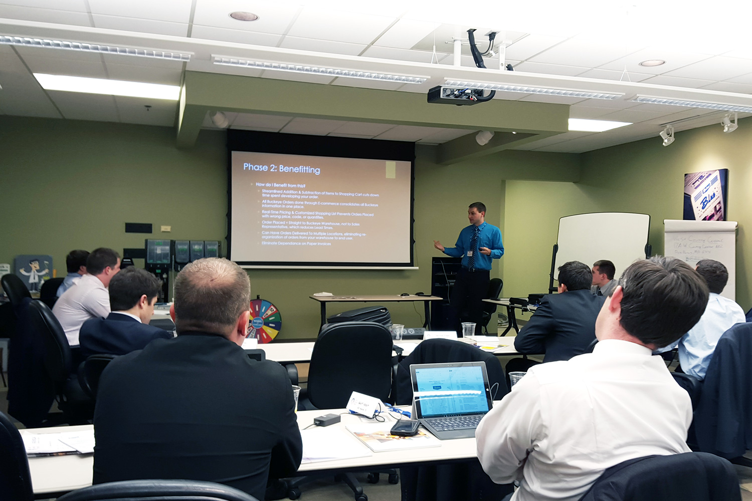 Man presenting with projector to a room full of the sales team.