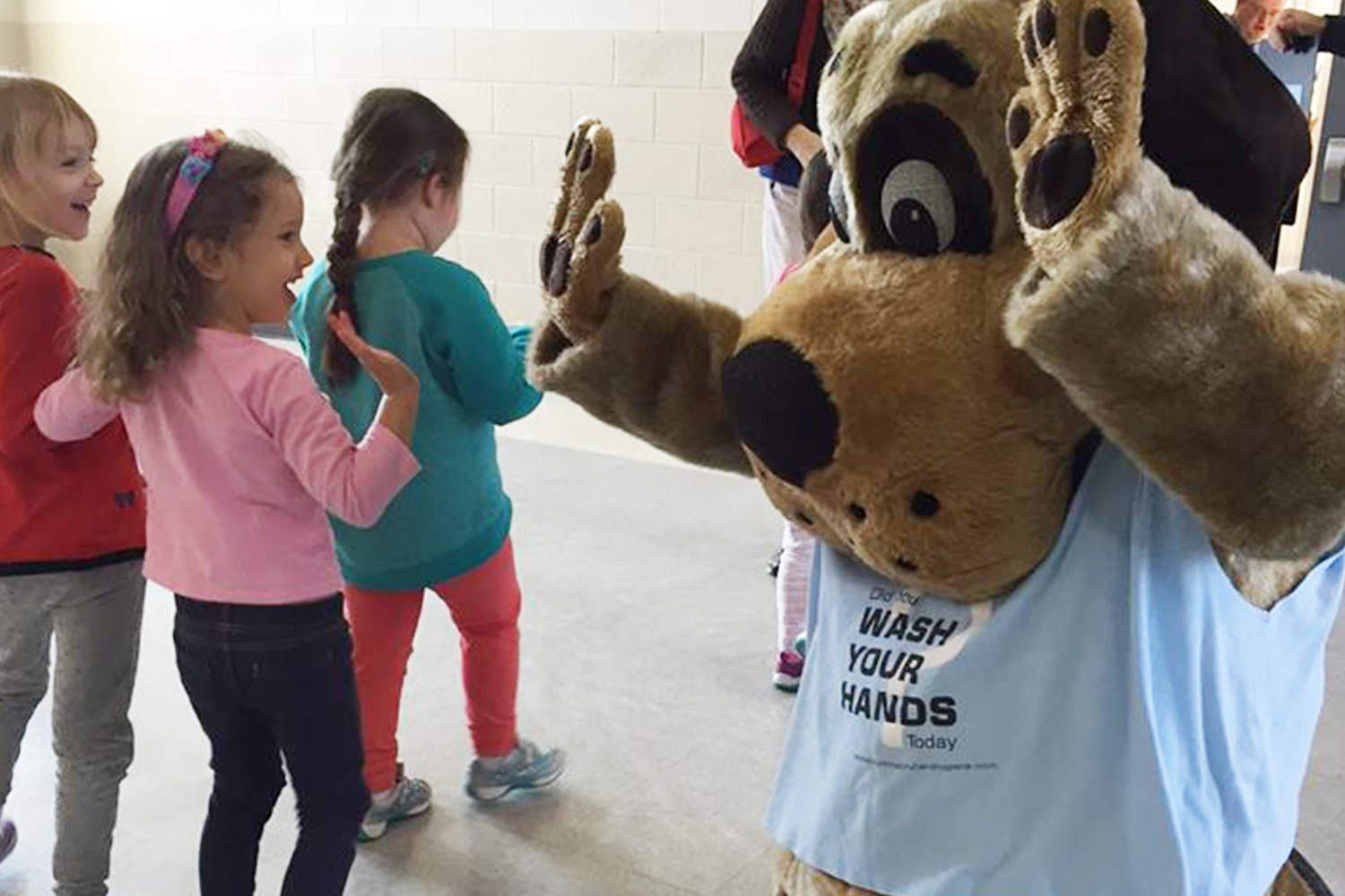 Biscuit the dog high-fiving a young student