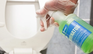 Terminator spray bottle disinfecting a toilet seat