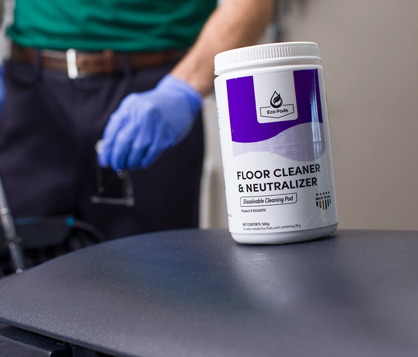 A gloved hand dropping an Eco Pod into Nilfisk Autoscrubber