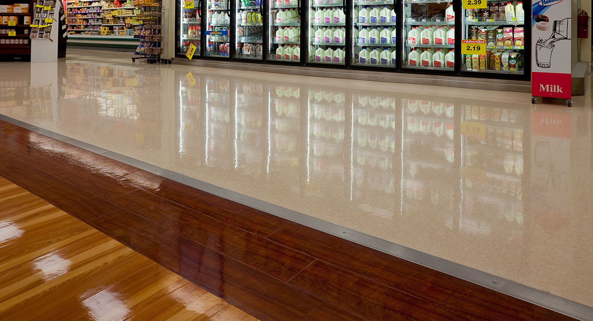 A shiny floor in a grocery store next to a refrigerated section