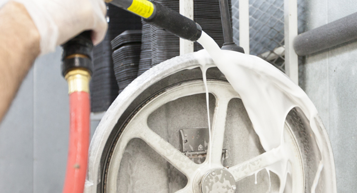 A hose spraying foaming liquid on industrial machine